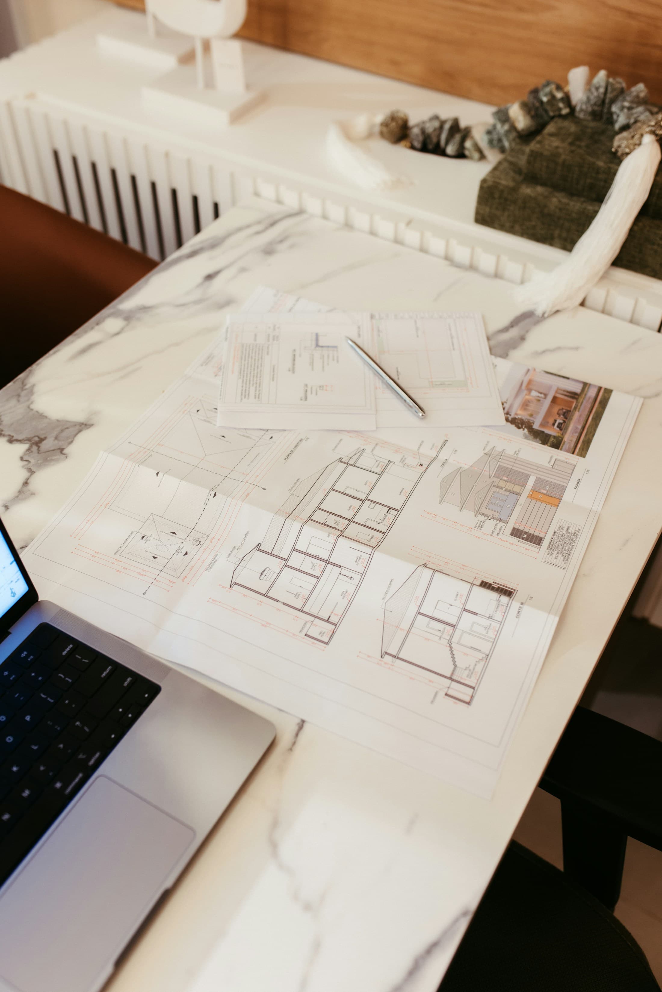 Architectural plans and a laptop on a working desk
